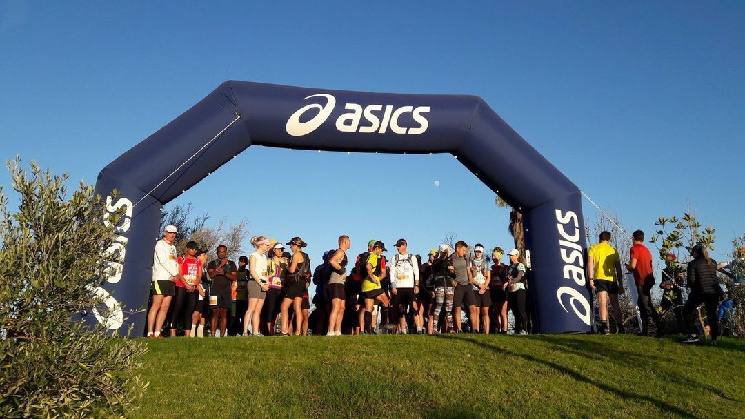 Asics-branded inflatable finish arch with runners gathered at the start of a race