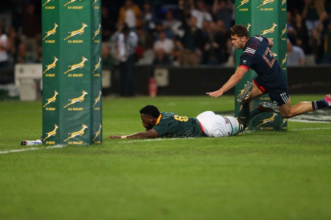 Springboks players in action in front of branded pitch-side boards